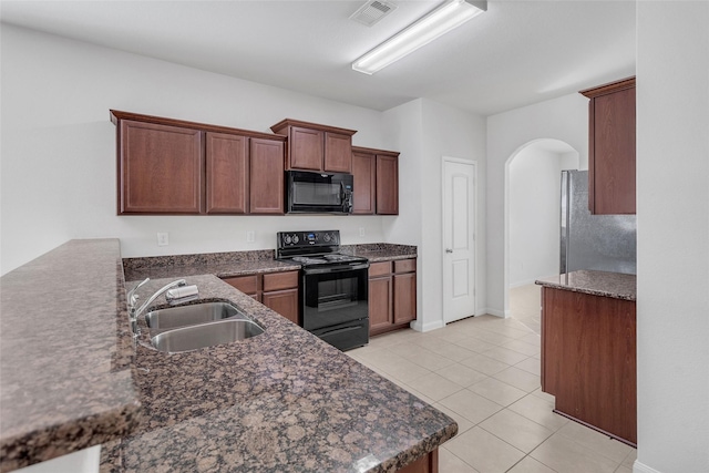 kitchen with kitchen peninsula, sink, black appliances, light tile patterned floors, and dark stone countertops