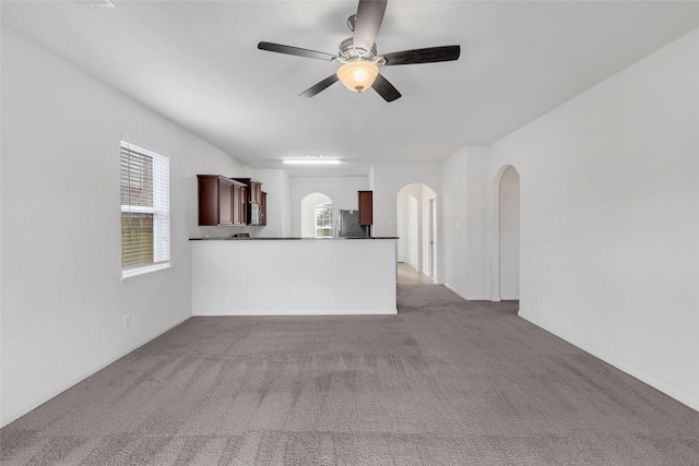 unfurnished living room featuring ceiling fan, carpet floors, and a healthy amount of sunlight