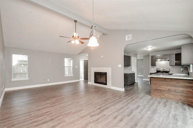 unfurnished living room featuring a wealth of natural light, lofted ceiling with beams, sink, and light hardwood / wood-style floors