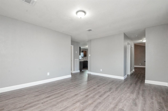 empty room with a textured ceiling and light hardwood / wood-style flooring