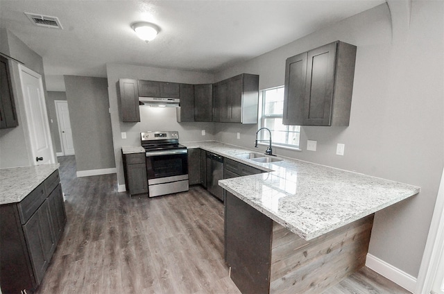 kitchen with sink, stainless steel appliances, a kitchen breakfast bar, light stone counters, and kitchen peninsula