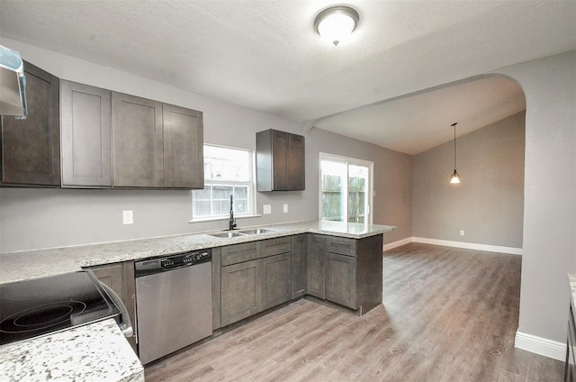 kitchen featuring kitchen peninsula, stainless steel dishwasher, sink, pendant lighting, and lofted ceiling