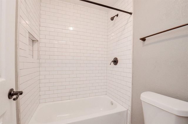 bathroom featuring toilet and tiled shower / bath