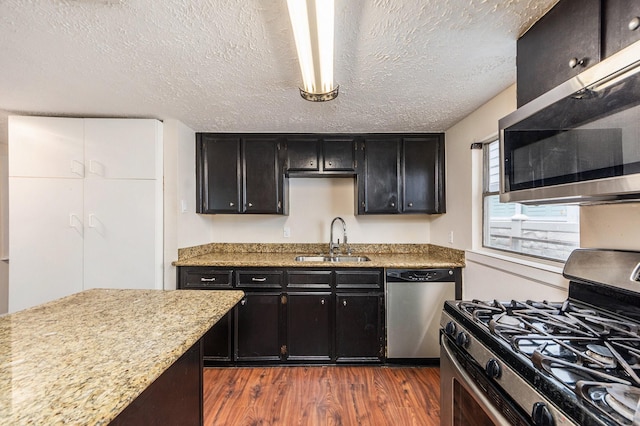 kitchen featuring a textured ceiling, stainless steel appliances, dark wood-type flooring, and sink