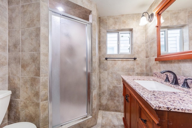 bathroom featuring plenty of natural light, vanity, tile walls, and toilet