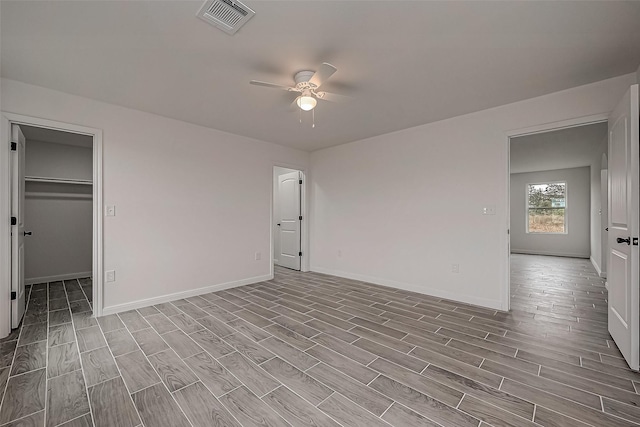 unfurnished bedroom featuring light wood-type flooring, a walk in closet, a closet, and ceiling fan