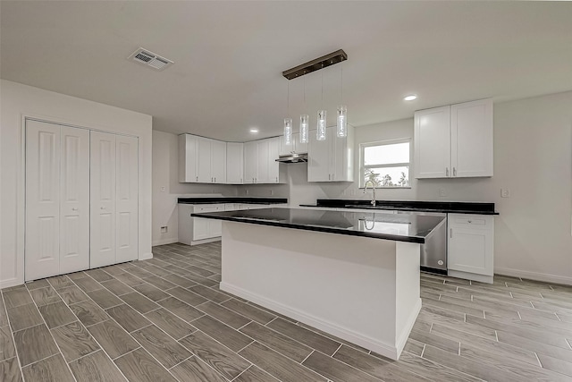 kitchen featuring pendant lighting, a center island, white cabinetry, and sink