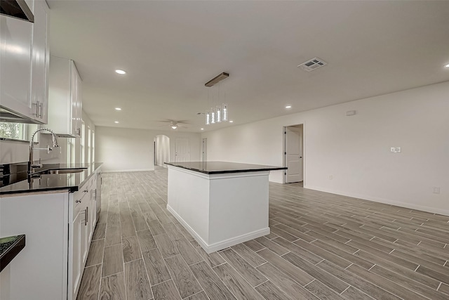 kitchen featuring white cabinetry, sink, ceiling fan, decorative light fixtures, and a kitchen island