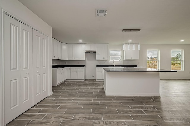 kitchen featuring white cabinets, a kitchen island, and hanging light fixtures