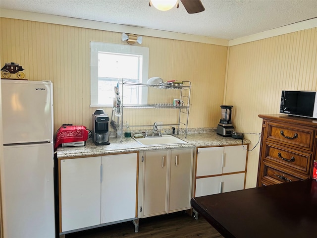 kitchen with a textured ceiling, ceiling fan, dark wood-type flooring, sink, and white fridge