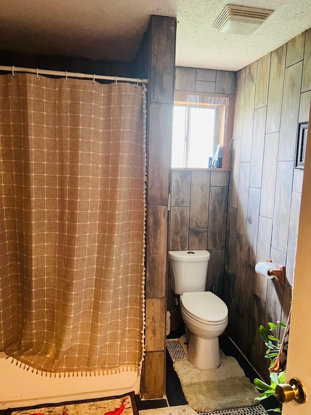 bathroom with curtained shower, a textured ceiling, and toilet