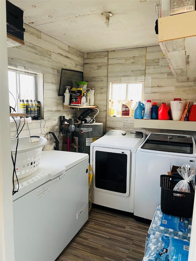 clothes washing area with laundry area, washer and clothes dryer, dark wood finished floors, and wood walls