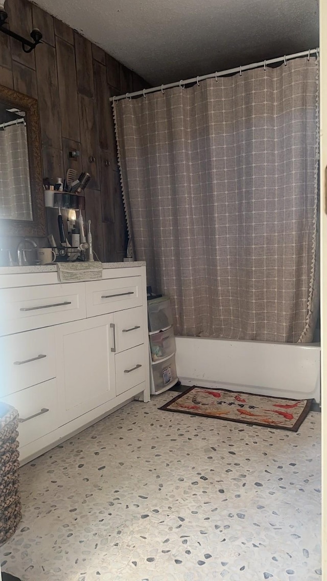 bathroom with wood walls, shower / bath combination with curtain, and a textured ceiling