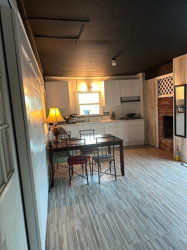 kitchen featuring black gas cooktop, a sink, white cabinets, light countertops, and light wood-type flooring