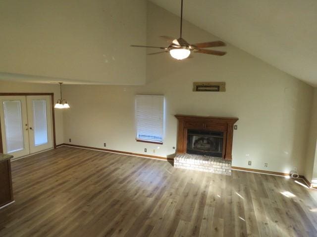 unfurnished living room with ceiling fan with notable chandelier, wood-type flooring, high vaulted ceiling, and french doors