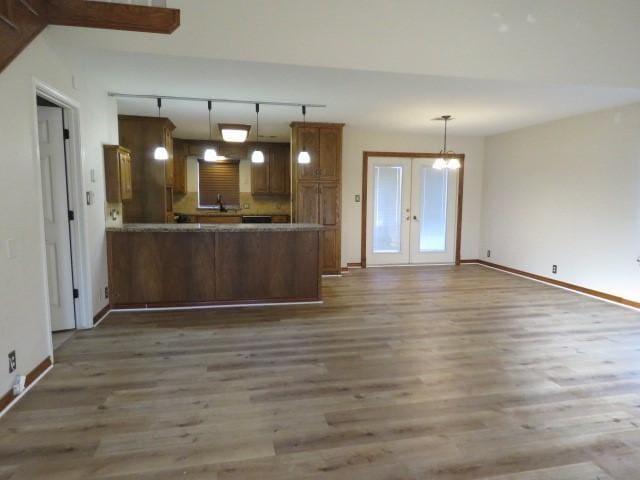 kitchen featuring kitchen peninsula, french doors, hanging light fixtures, and hardwood / wood-style floors