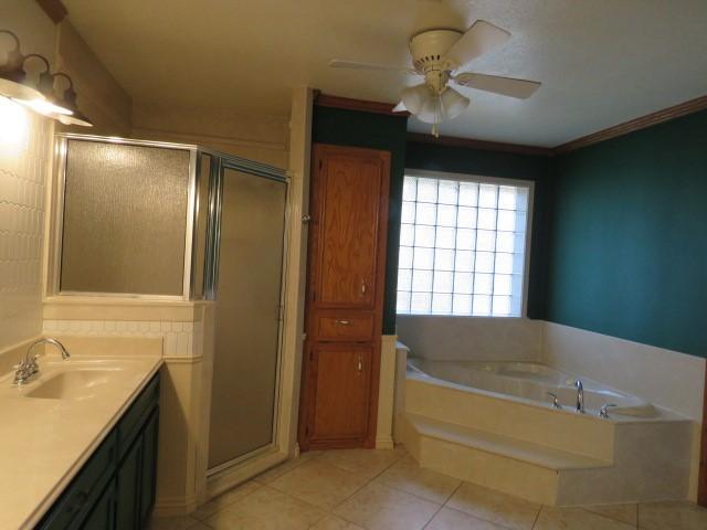 bathroom featuring ceiling fan, plus walk in shower, tile patterned flooring, crown molding, and vanity