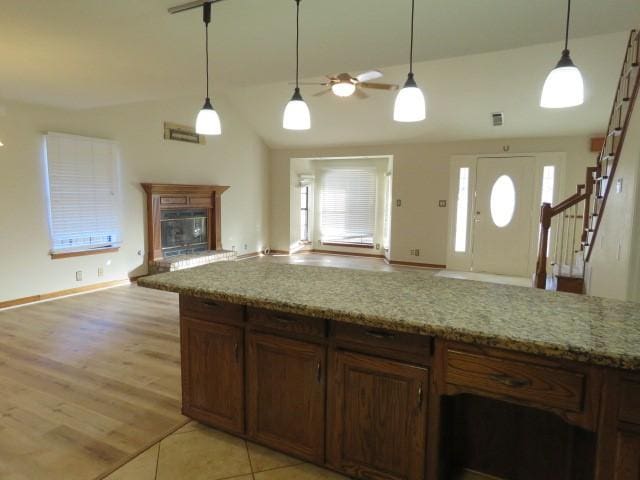 kitchen featuring light stone countertops, ceiling fan, hanging light fixtures, and vaulted ceiling