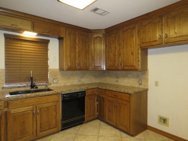 kitchen with light stone counters, dishwasher, and sink