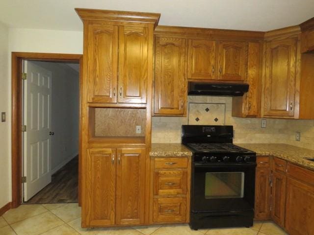 kitchen with tasteful backsplash, black range with gas stovetop, light stone counters, and light tile patterned floors