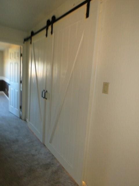 hallway featuring a barn door and carpet floors