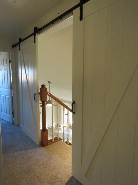 staircase with a barn door and carpet floors