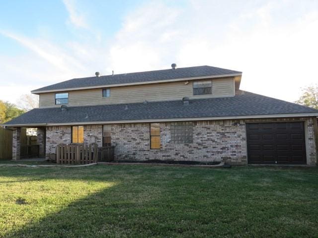 rear view of property featuring a garage and a yard