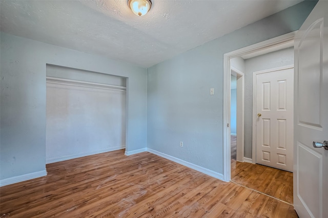 unfurnished bedroom with a closet, a textured ceiling, and light wood-type flooring