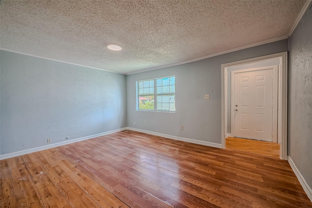 spare room featuring hardwood / wood-style floors, a textured ceiling, and crown molding