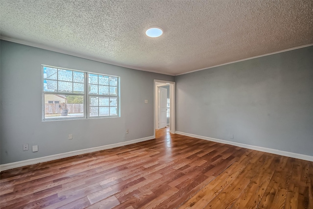 empty room with wood-type flooring, a textured ceiling, and ornamental molding