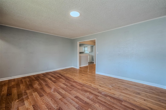 spare room with crown molding, light hardwood / wood-style floors, and a textured ceiling