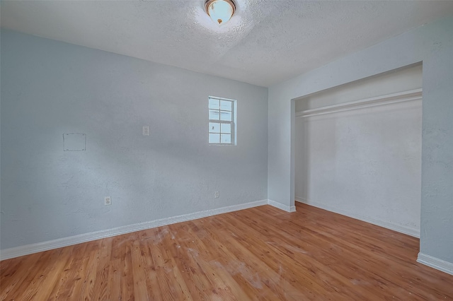 unfurnished bedroom featuring light hardwood / wood-style floors, a textured ceiling, and a closet