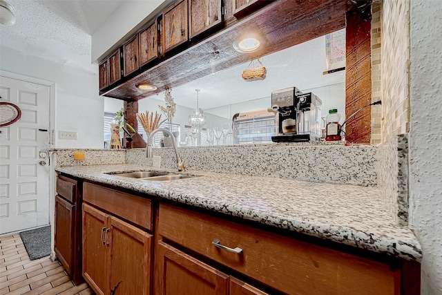 kitchen with a textured ceiling, a notable chandelier, and sink