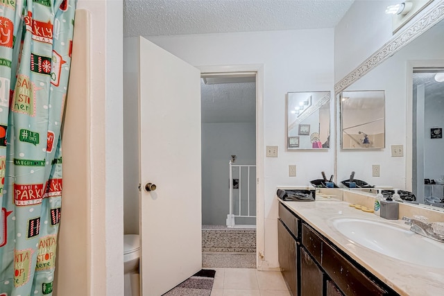 bathroom with tile patterned floors, vanity, toilet, and a textured ceiling