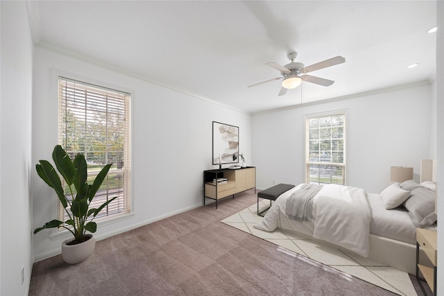 bedroom featuring multiple windows, ceiling fan, light carpet, and ornamental molding