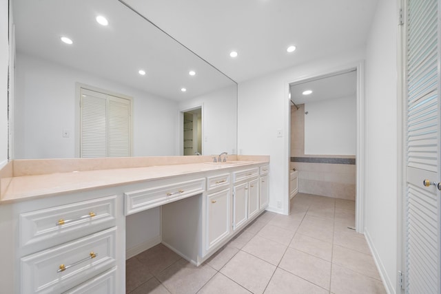 bathroom featuring tile patterned flooring, vanity, and tiled tub