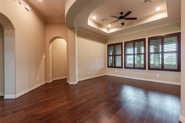 empty room featuring dark hardwood / wood-style floors, ceiling fan, and a raised ceiling