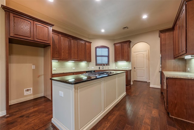 kitchen with a kitchen island, dark hardwood / wood-style floors, dark stone counters, and stainless steel gas cooktop