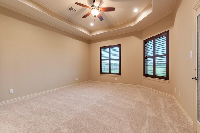 carpeted spare room featuring crown molding, ceiling fan, and a raised ceiling