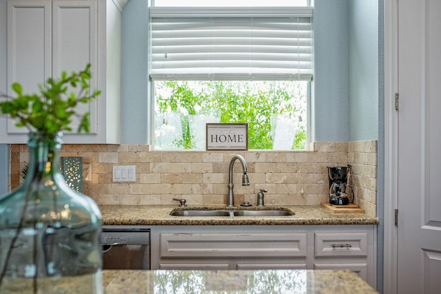 kitchen featuring light stone countertops, dishwasher, sink, white cabinetry, and tasteful backsplash