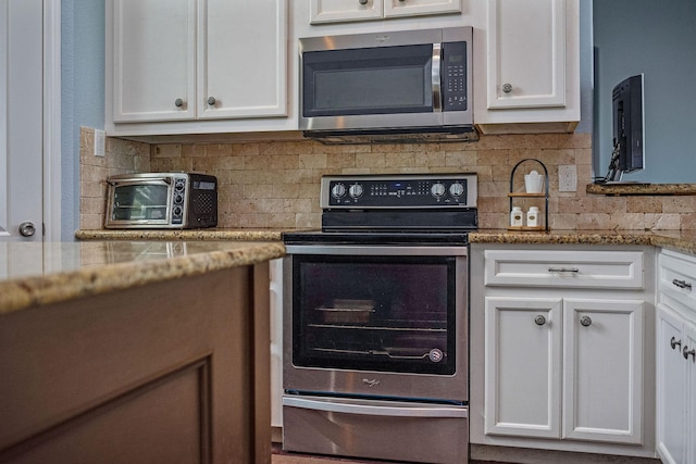 kitchen featuring white cabinets, decorative backsplash, stainless steel appliances, and light stone counters