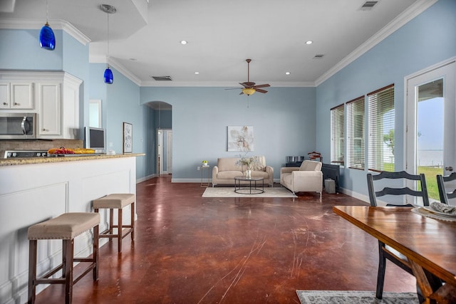 kitchen with ornamental molding, ceiling fan, decorative light fixtures, white cabinets, and a breakfast bar area