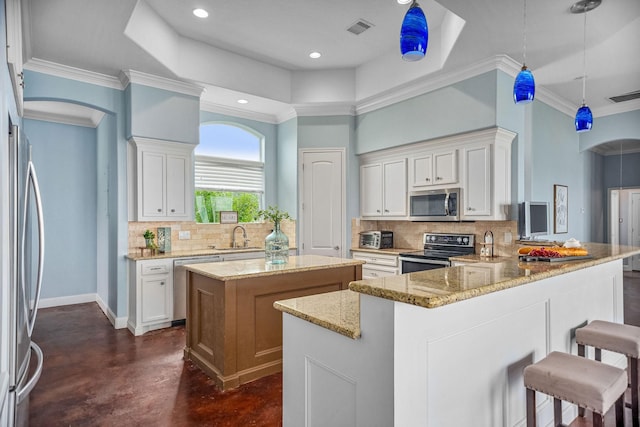 kitchen with kitchen peninsula, light stone counters, stainless steel appliances, pendant lighting, and white cabinetry