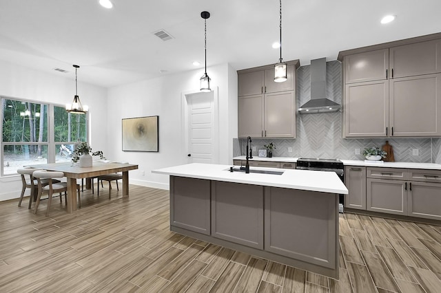 kitchen with sink, hanging light fixtures, gray cabinetry, and wall chimney range hood