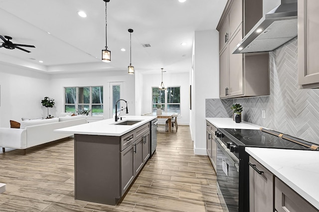 kitchen featuring sink, hanging light fixtures, wall chimney range hood, tasteful backsplash, and appliances with stainless steel finishes