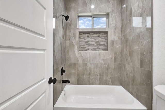 bathroom featuring tiled shower / bath combo and toilet