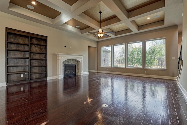 unfurnished living room with baseboards, coffered ceiling, wood finished floors, and a glass covered fireplace