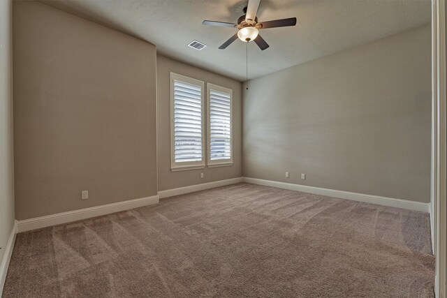 carpeted empty room featuring ceiling fan, visible vents, and baseboards