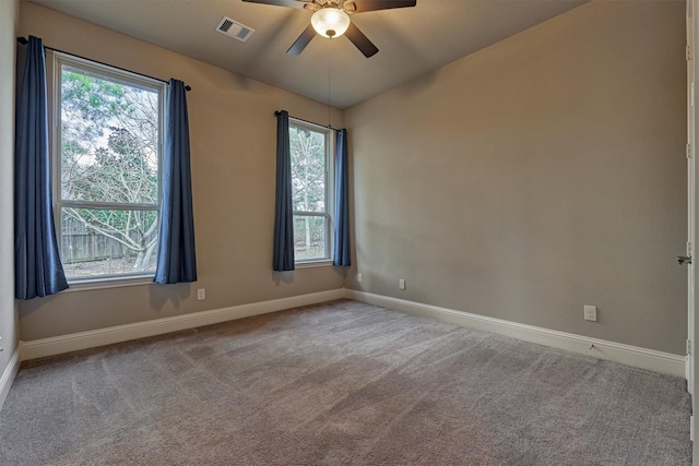 carpeted spare room with a ceiling fan, visible vents, and baseboards