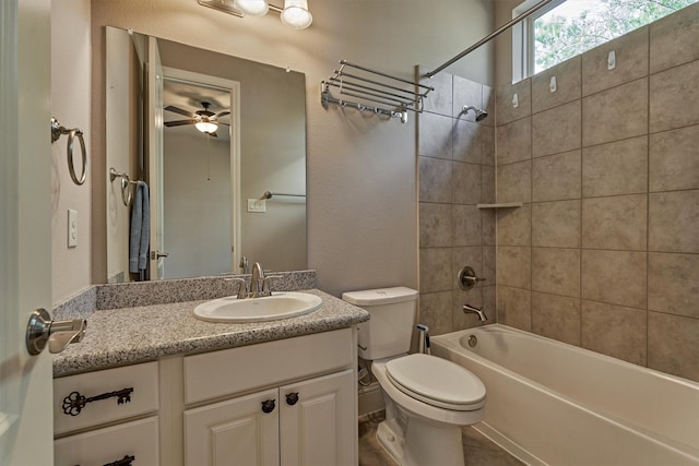 full bathroom featuring ceiling fan, tiled shower / bath, vanity, and toilet